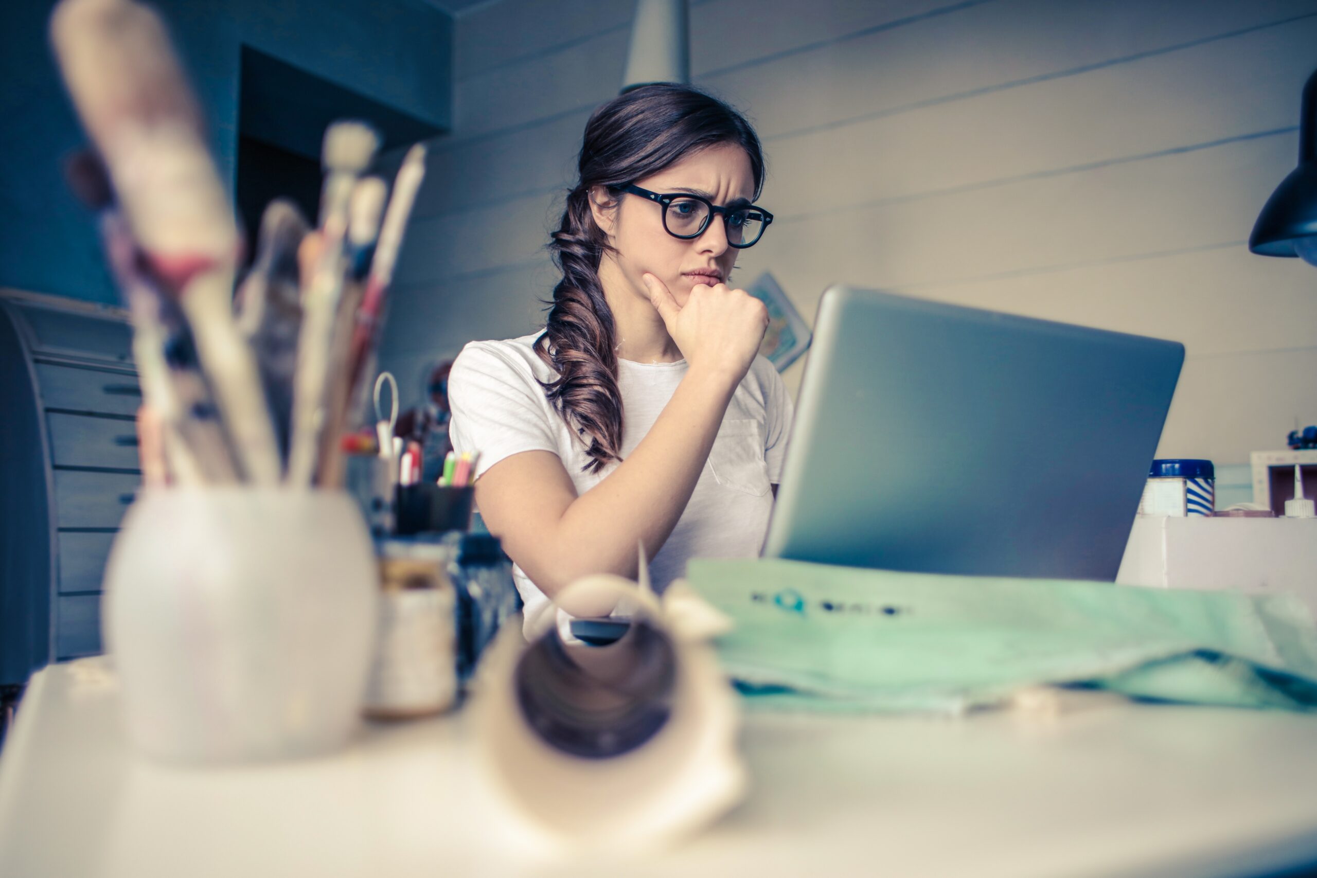 Lady in front of computer with a perplexed expression and hand on her chin